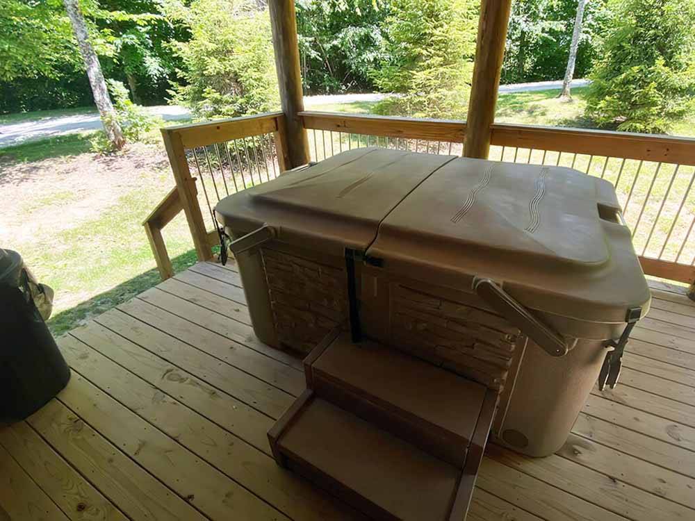 Hot tub that is covered on wooden deck at PINE CREEK CABINS AND CAMPGROUND