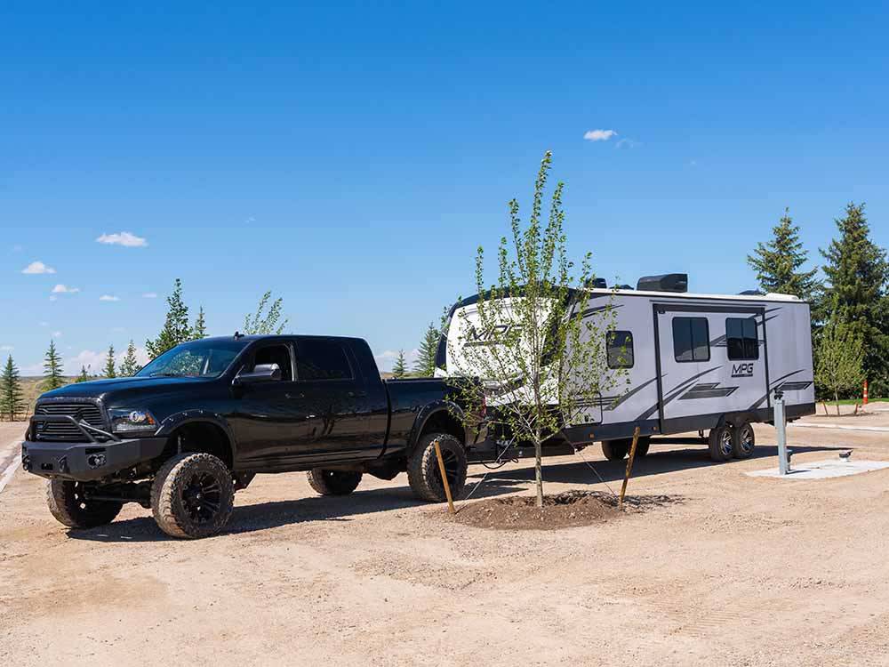 A black truck and trailer parked in a dirt site at LITTLE AMERICA RV PARK