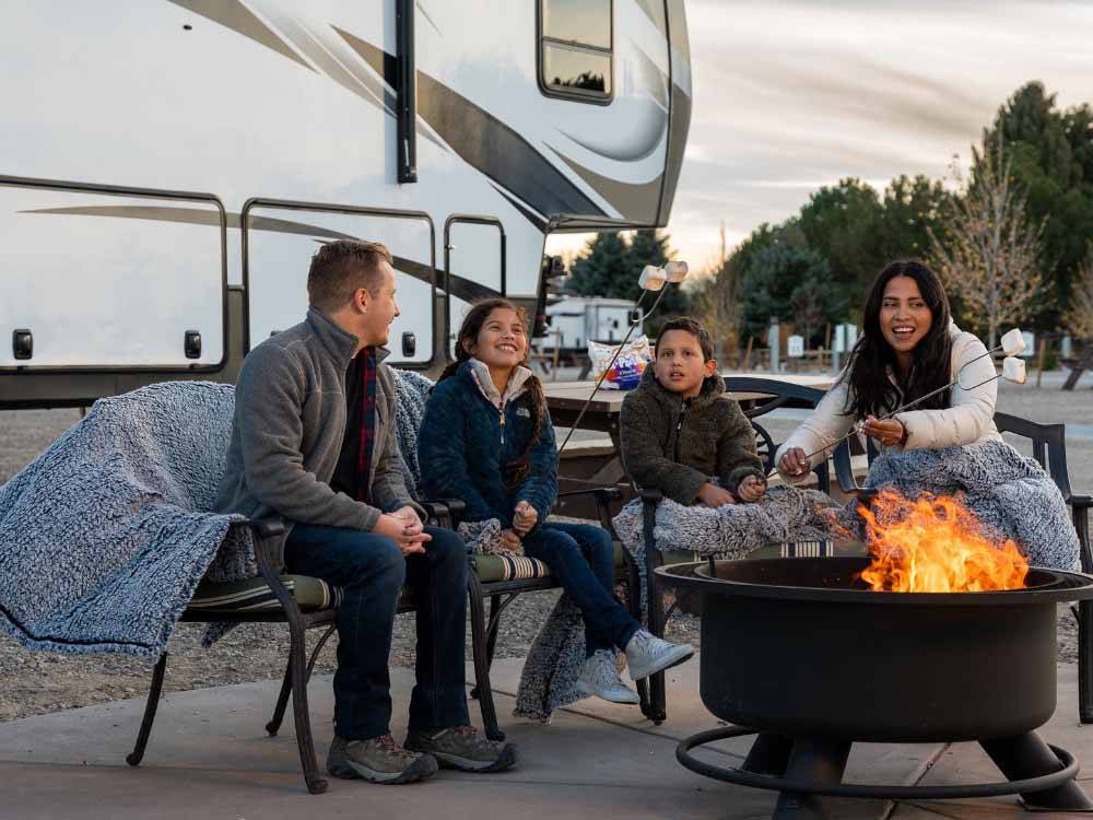 A family roasting marshmallows next to their RV at LITTLE AMERICA RV PARK