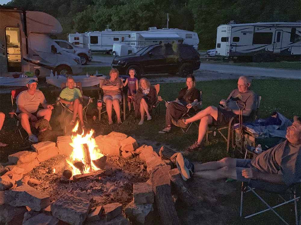 A group of people sitting around a fire pit at DENTON FERRY RV PARK & CABIN RENTAL