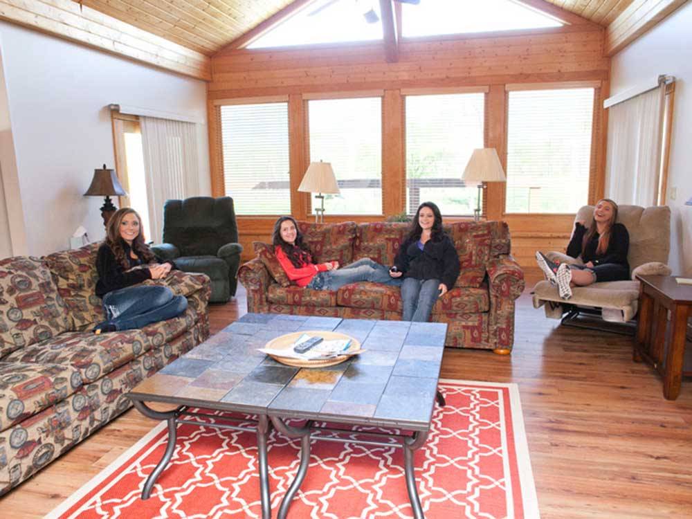 Girls on sofas and recliner watching television at DENTON FERRY RV PARK & CABIN RENTAL