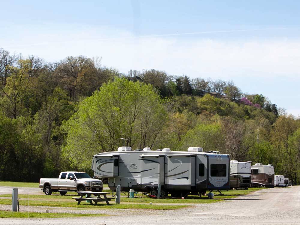Row of RV campsites at the foot of a hill at DENTON FERRY RV PARK & CABIN RENTAL