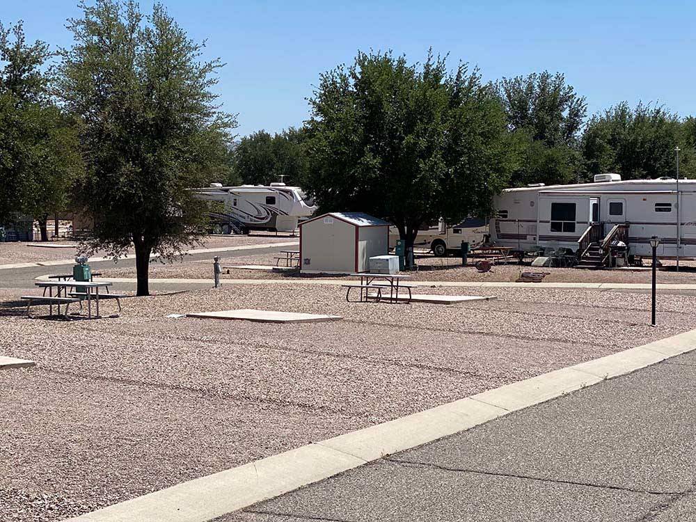Gravel RV sites separated by trees at DE ANZA RV RESORT