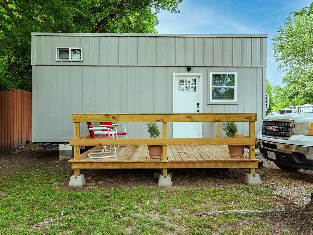 Wooden patio with red chairs and railing attached to park model at K & R RV PARK