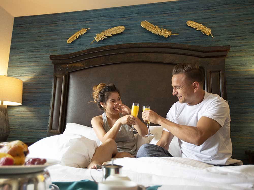 A couple sitting in bed drinking orange juice at LITTLE RIVER CASINO RESORT RV PARK
