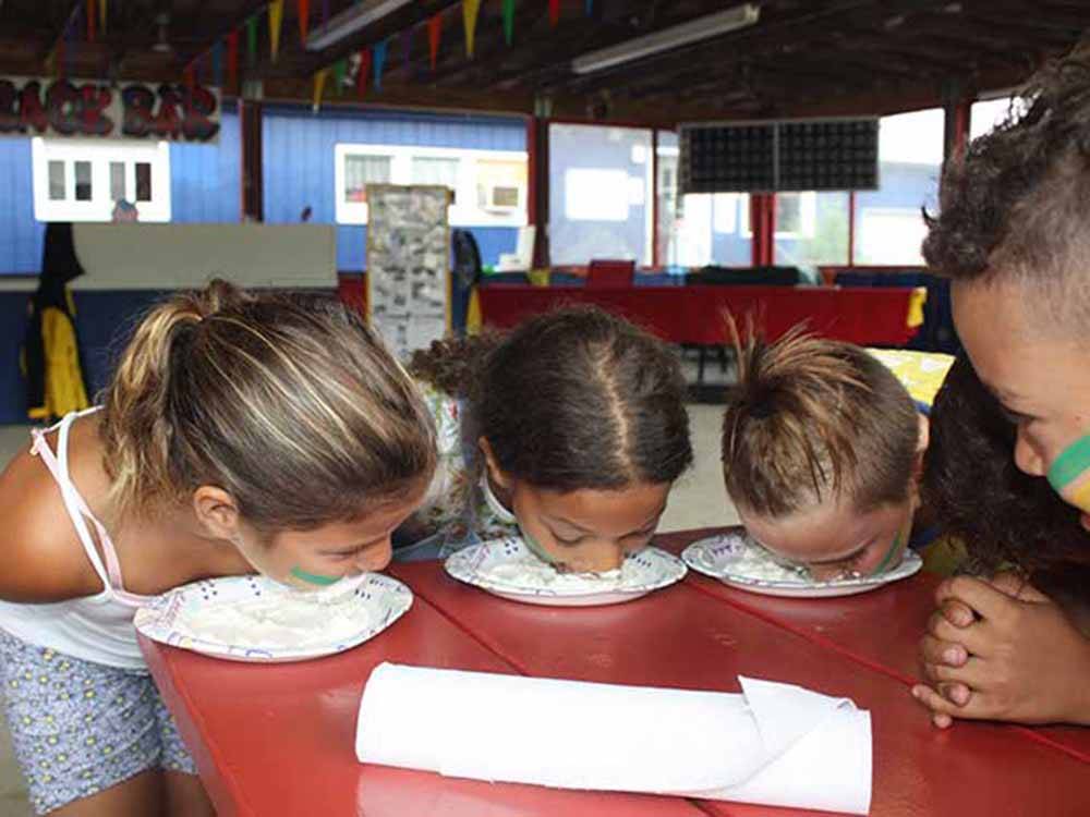 Children having a pie eating contest at STATELINE CAMPRESORT & CABINS