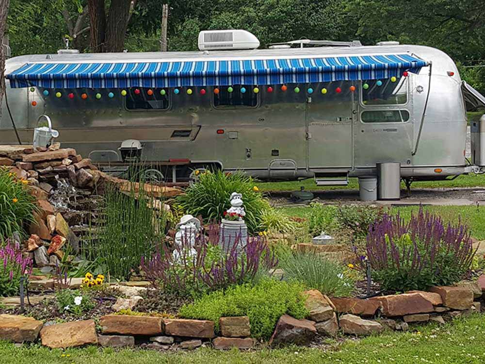 Trailer parked in front of a garden area at RIVERSIDE RV PARK