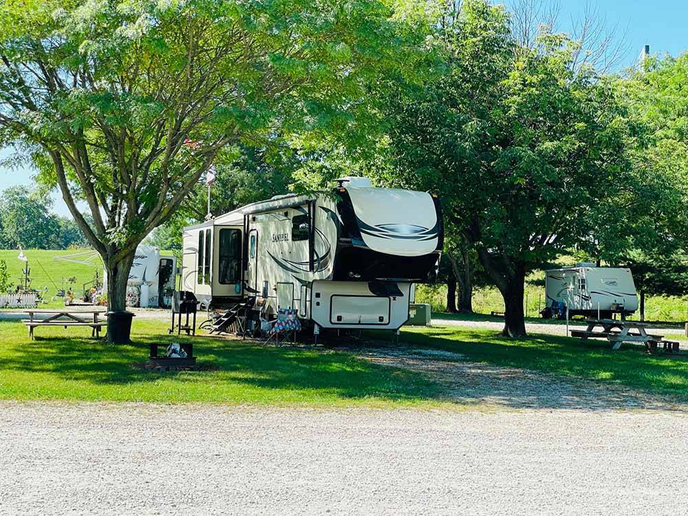 Tree lined campsite with camper at NEW VISION RV PARK