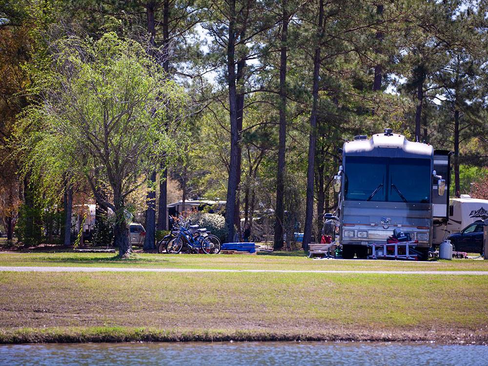A Class A motorhome parked next to the water at WILLOWTREE RV RESORT & CAMPGROUND
