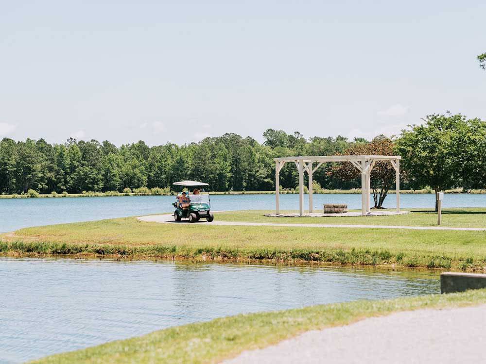 Two ladies in a golf cart by the lake at WILLOWTREE RV RESORT & CAMPGROUND