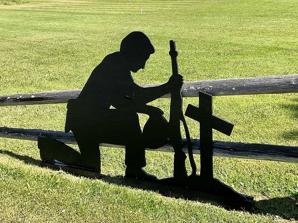 A silhouette of a soldier kneeling in front of a cross at PUMPKIN PATCH RV RESORT