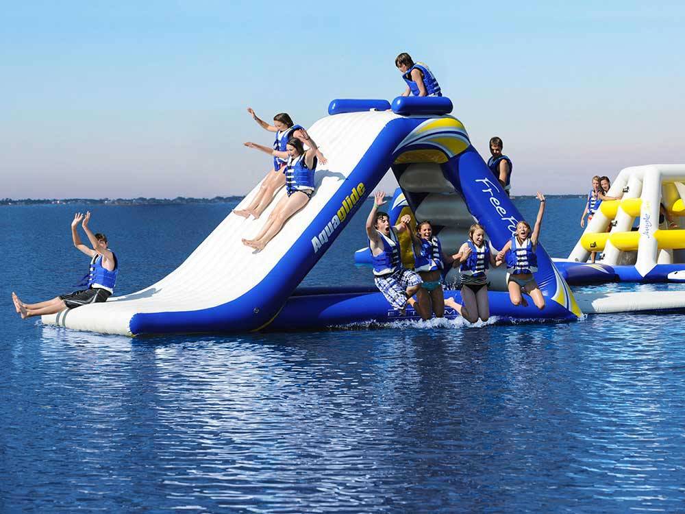 Kids playing on the inflatables in the water at EMERALD LAKE TRAILER RESORT & WATERPARK