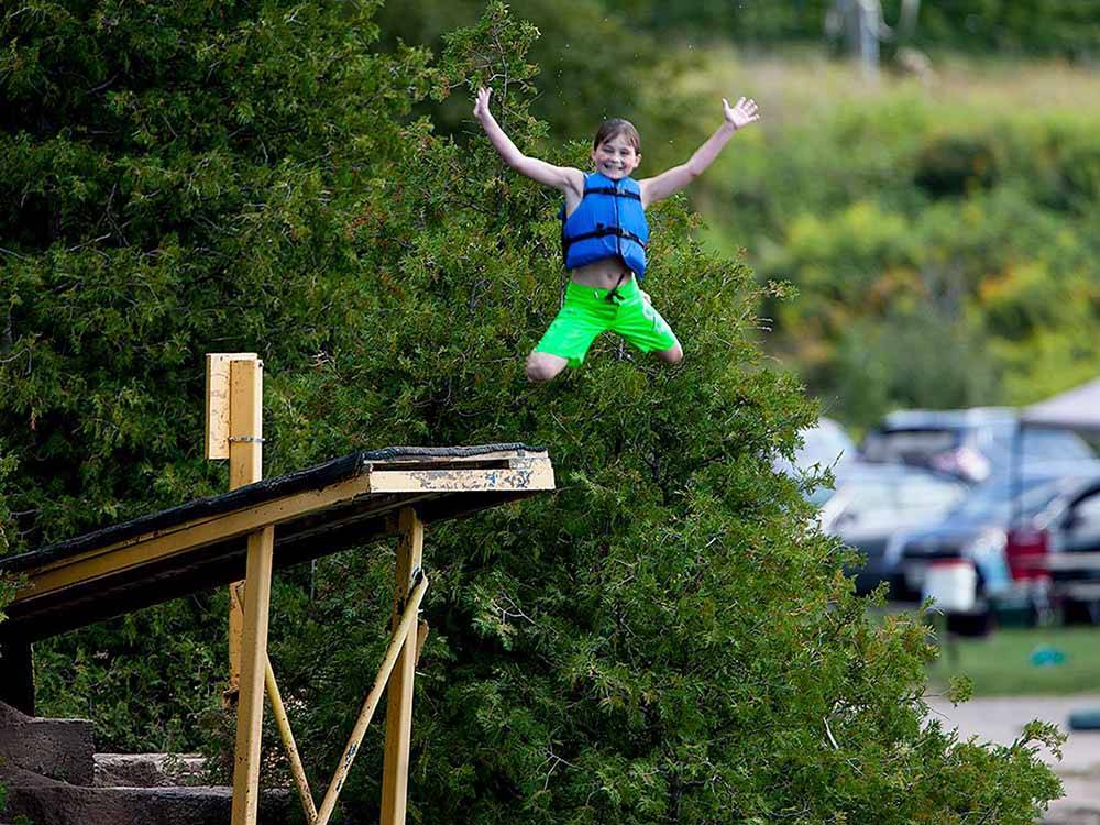 A kid jumping off a dock at EMERALD LAKE TRAILER RESORT & WATERPARK