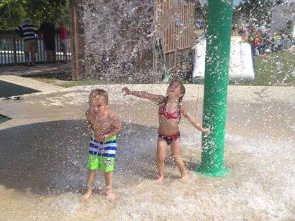 A couple of kids playing in the splash pad at EMERALD LAKE TRAILER RESORT & WATERPARK