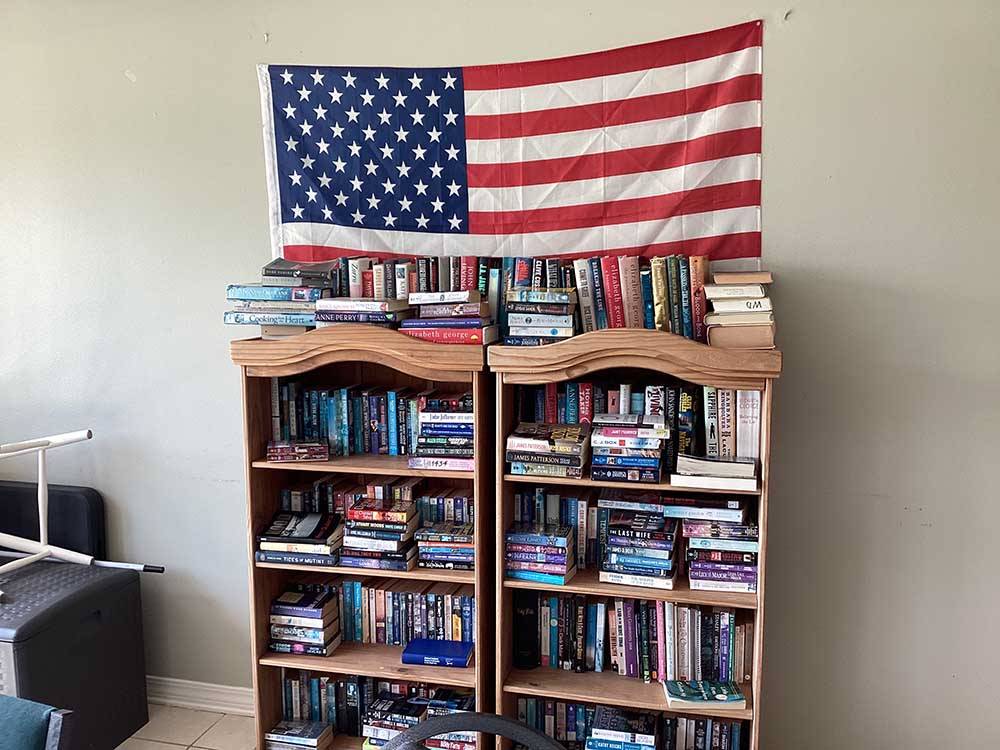 A book shelf with a USA flag hanging above it at RV HIDEAWAY CAMPGROUND