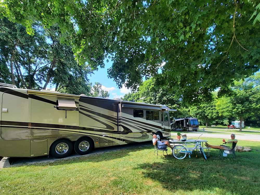 A couple sitting outside of their motorhome at WHITE ACRES CAMPGROUND