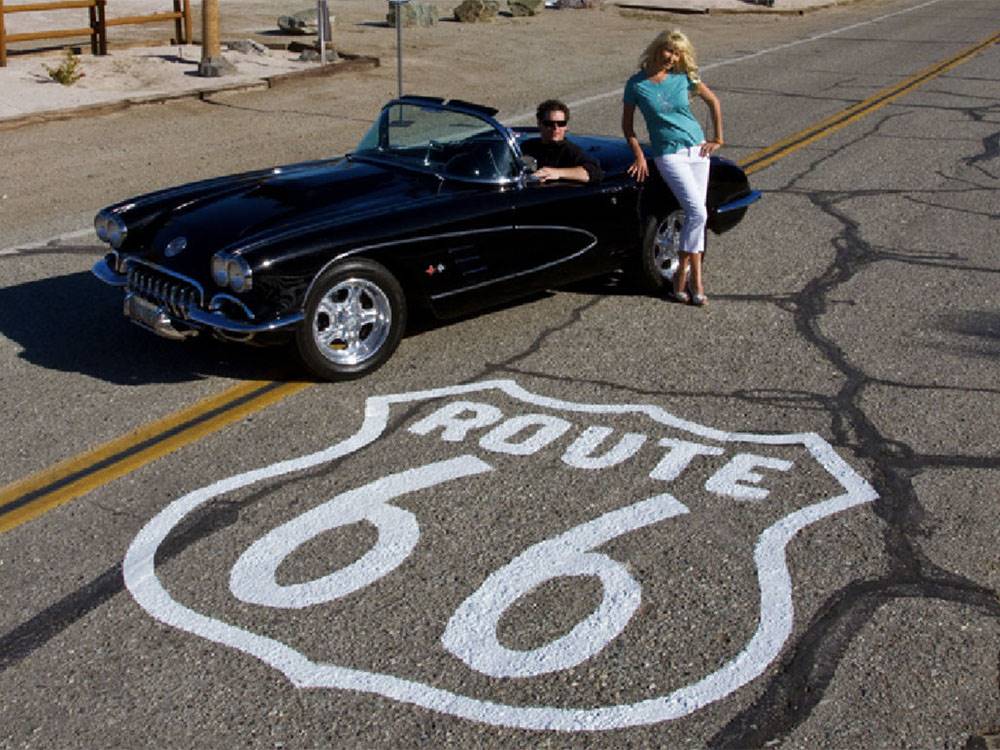 A man and lady parked in the road next to the Route 66 symbol at PIRATE COVE RESORT & MARINA