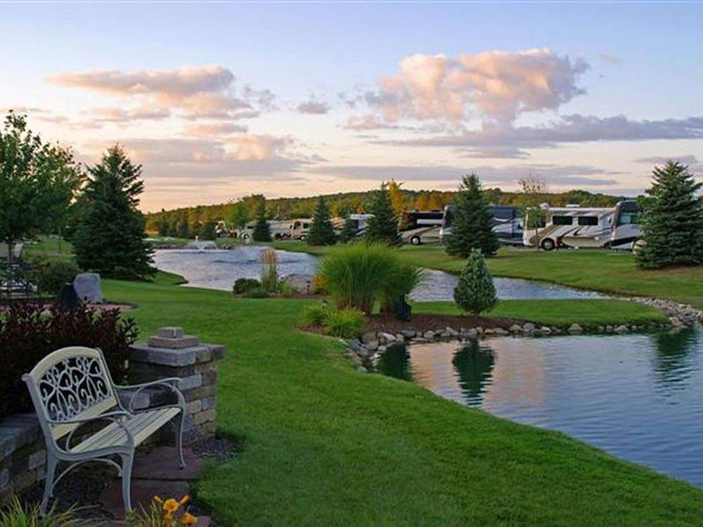 RVs parked near pretty lake and green grass at TRAVERSE BAY RV RESORT