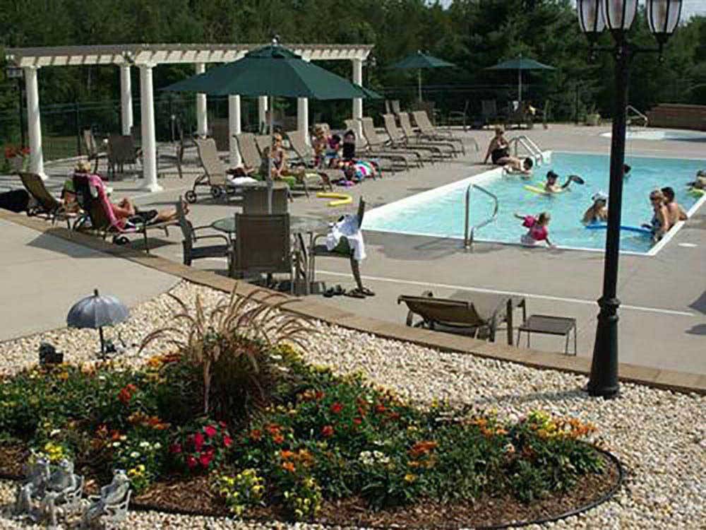 Campers swimming in pool, lounging pool side at TRAVERSE BAY RV RESORT