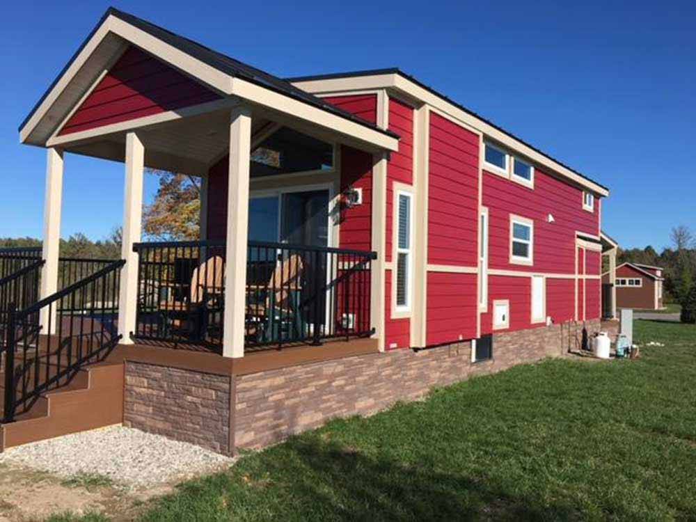 Park model painted red with porch at TRAVERSE BAY RV RESORT