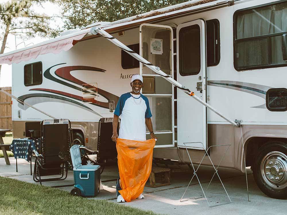 A man with a trash bag standing under an RV awning at LAKESIDE RV RESORT BY RJOURNEY