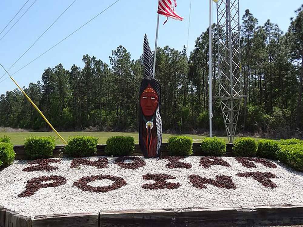 Indian statue next to rock sign at entrance at INDIAN POINT RV RESORT