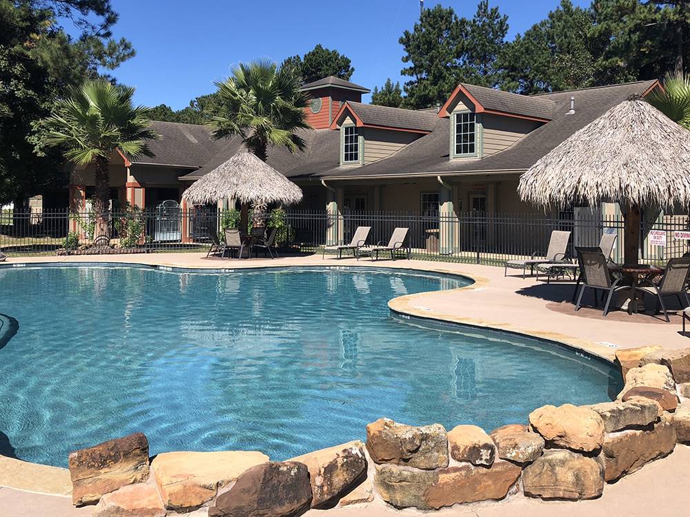Tiki umbrellas and chairs next to the swimming pool at RAYFORD CROSSING RV RESORT