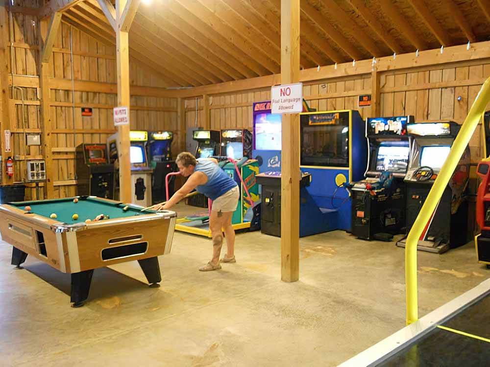 A woman playing pool at AMERICAN WILDERNESS CAMPGROUND
