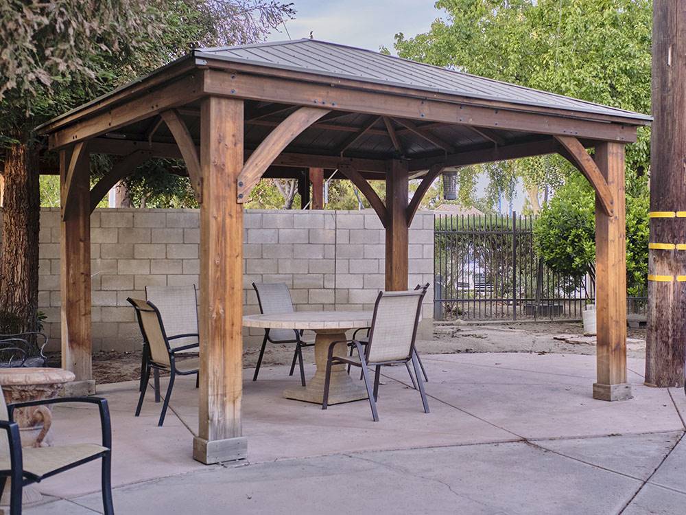 Wooden gazebo with a table and chairs at BAKERSFIELD RIVER RUN RV PARK