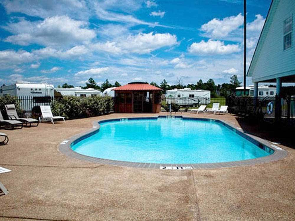 Community pool with showers in background at EZ DAZE RV PARK
