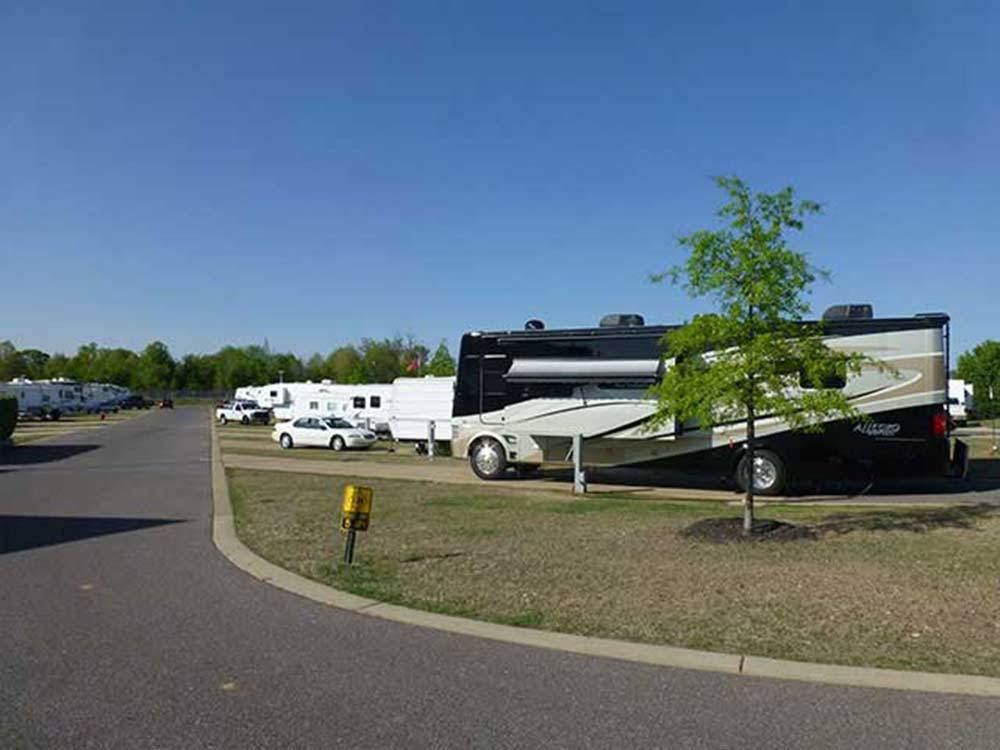 Large class A RV backed into open spot with lawn beside it at EZ DAZE RV PARK