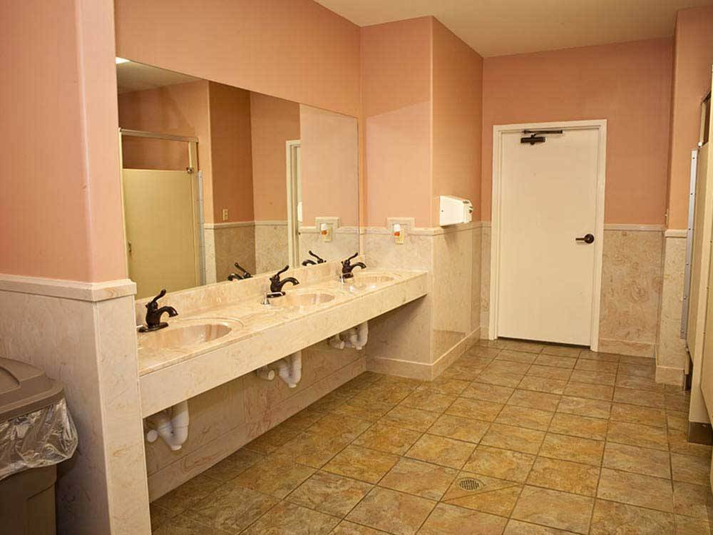 Pink hued restrooms with multiple sinks at EZ DAZE RV PARK