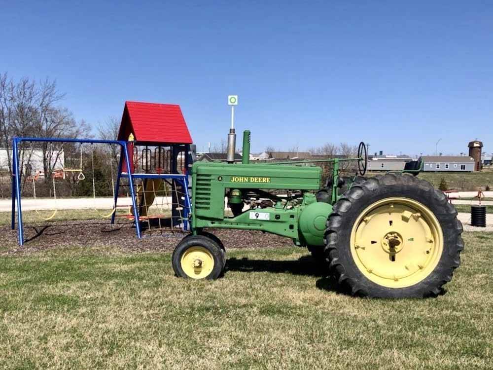 A John Deere tractor in front of the playground equipment at CROSSROADS RV PARK