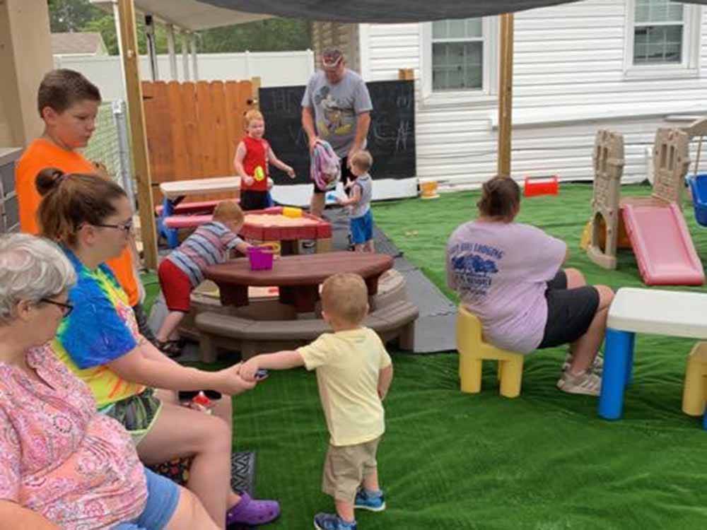 People watching kids playing on the playground at FOUR OAKS LODGING & RV RESORT