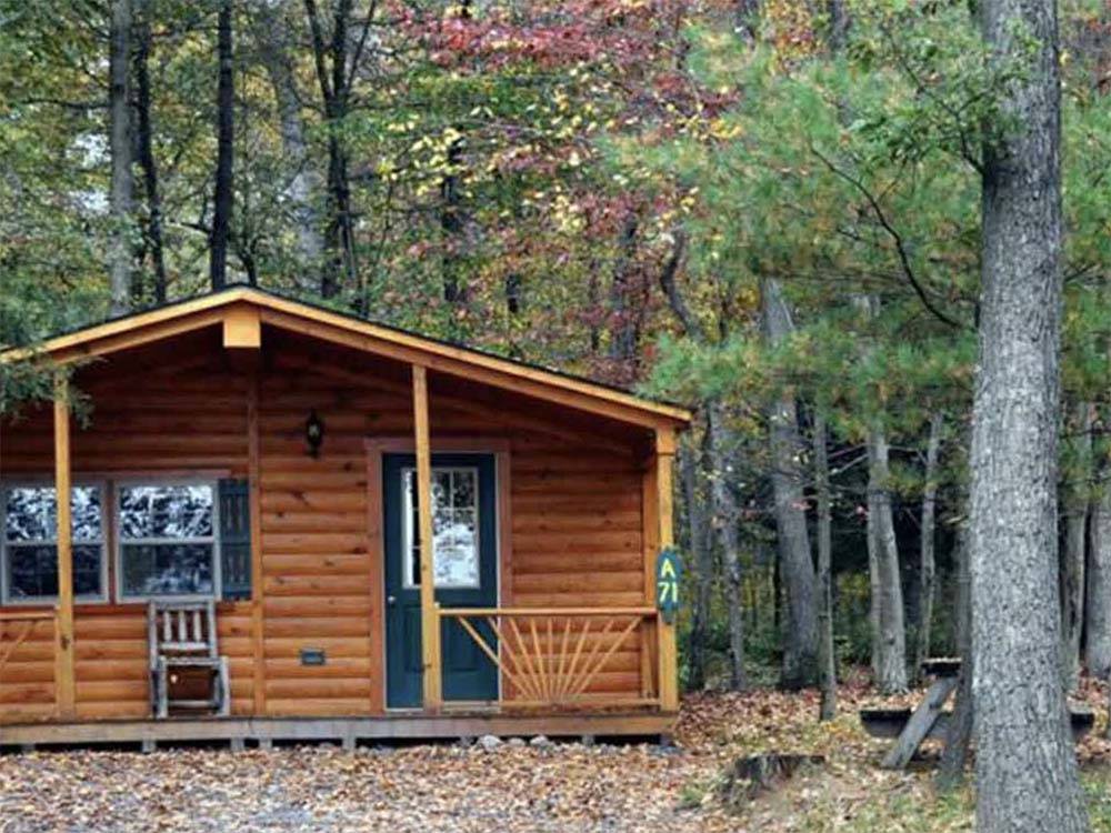 Cabin with a porch under autumn trees at MADISON VINES RV RESORT & COTTAGES