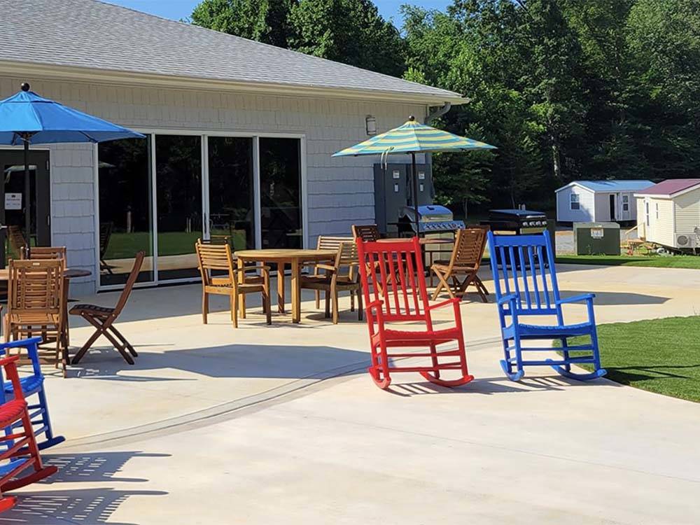 Red and blue rocking chairs and building under a sunny sky at MADISON VINES RV RESORT & COTTAGES
