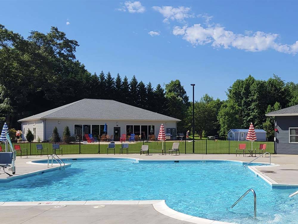 A pool with building in background at MADISON VINES RV RESORT & COTTAGES
