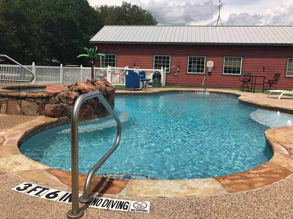 Swimming pool and hot tub adjacent to the enclosed rec hall and game room at COFFEE CREEK RV RESORT & CABINS