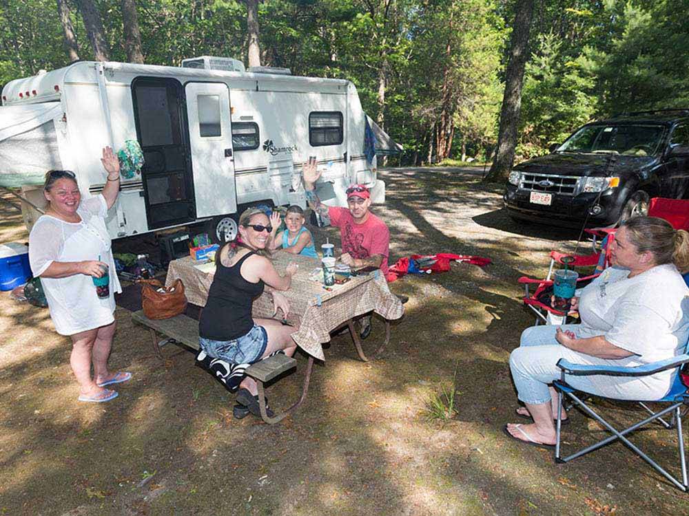 A group of people sitting around a travel trailer at CIRCLE CG FARM CAMPGROUND