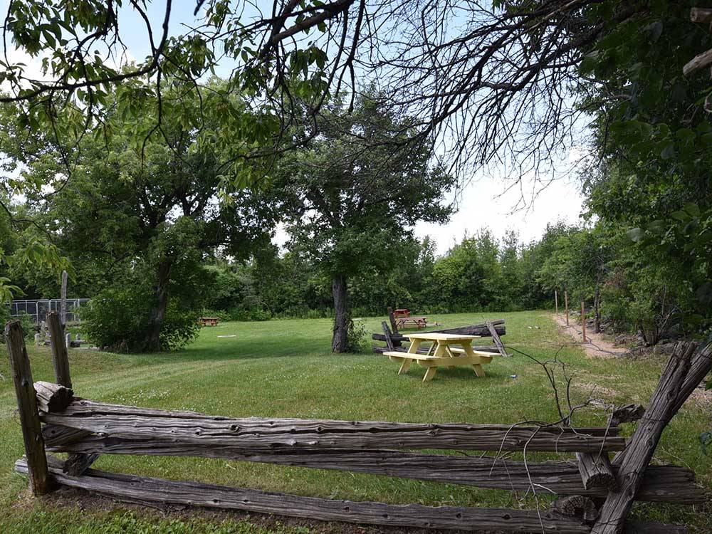 A yellow picnic table in a grassy campsite at CAMP HITHER HILLS
