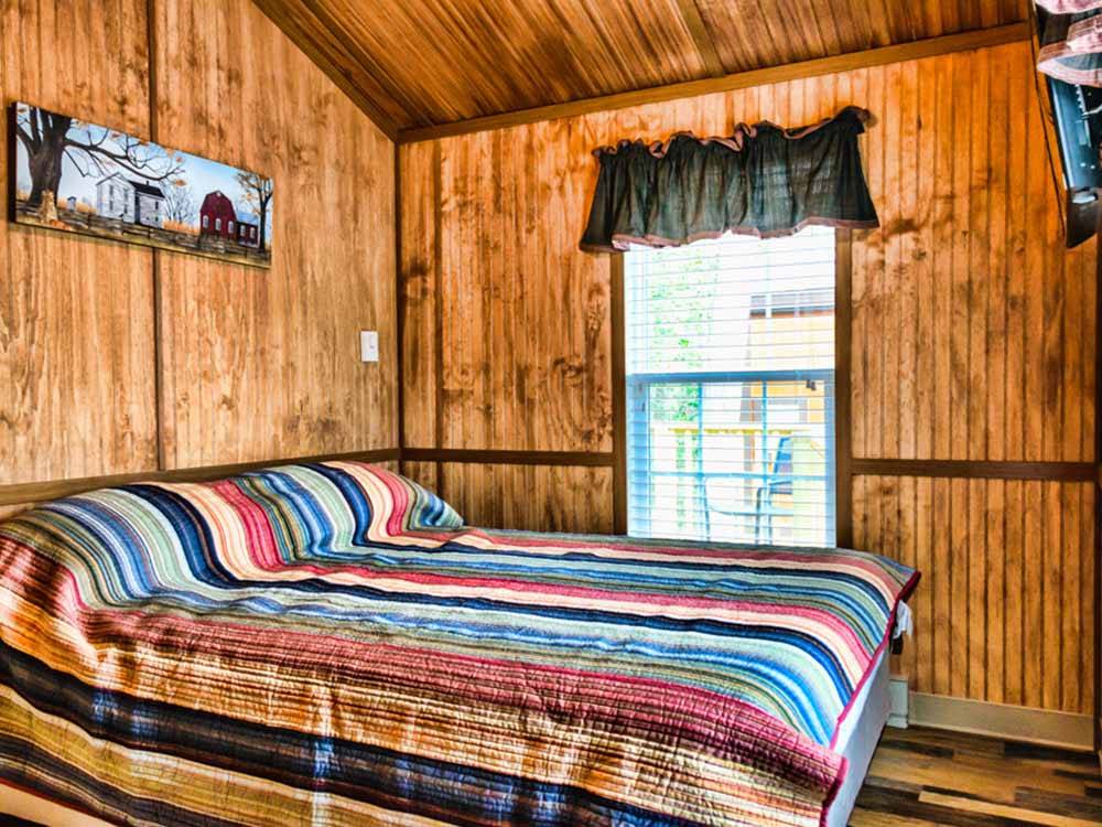 A bed with a striped bedspread at HATTERAS SANDS CAMPGROUND