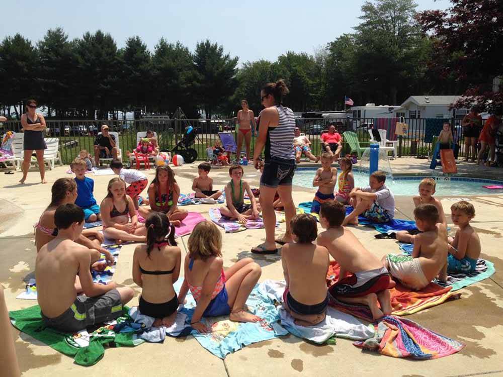 A group of kids sitting around a pool at SEA-VU CAMPGROUND