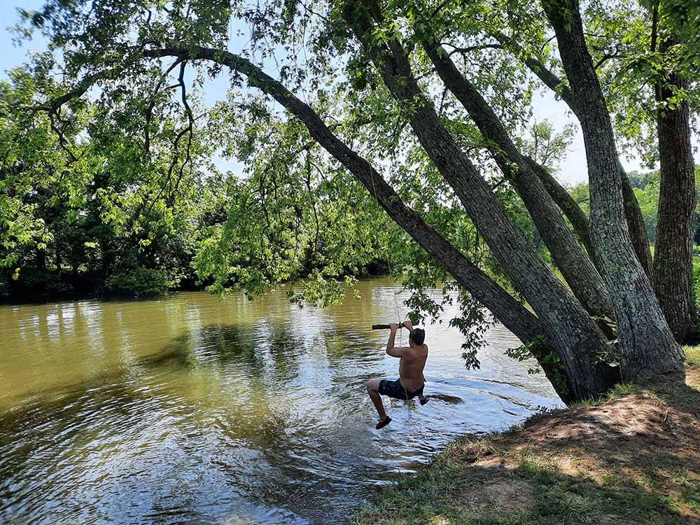 A kid on a rope swing going into the water at ELKHORN CREEK RV PARK