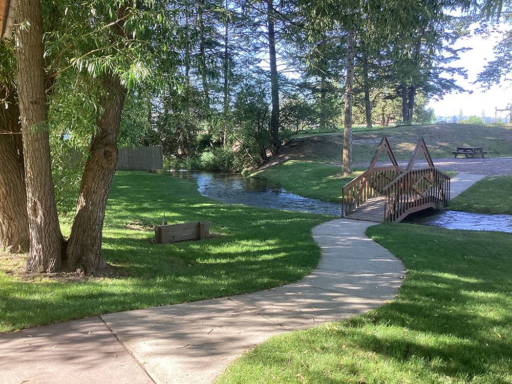 A wooden bridge over the stream at ROCKY MOUNTAIN 'HI' RV PARK AND CAMPGROUND