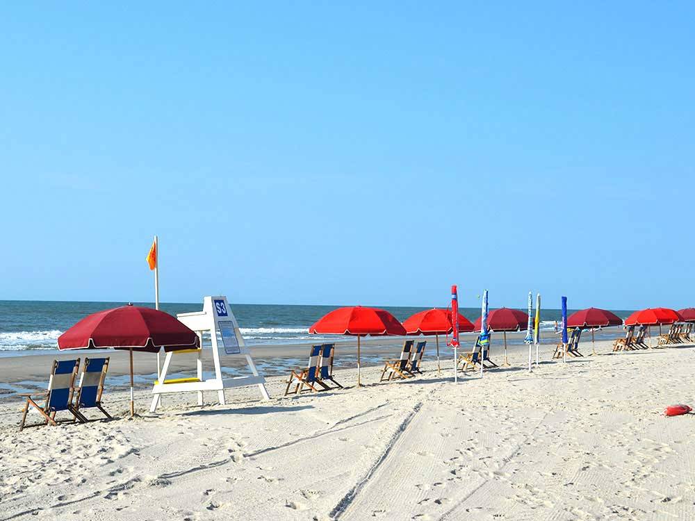Red umbrellas and chairs on the beach at OCEAN LAKES FAMILY CAMPGROUND