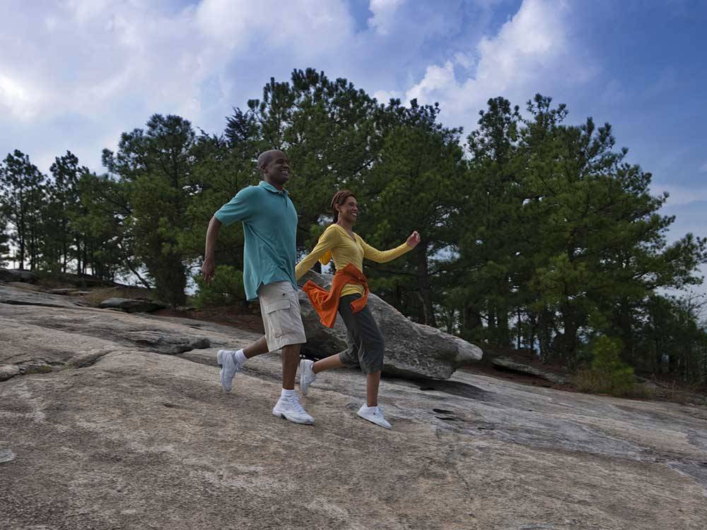 A couple holding hands walking down a mountain at STONE MOUNTAIN PARK CAMPGROUND