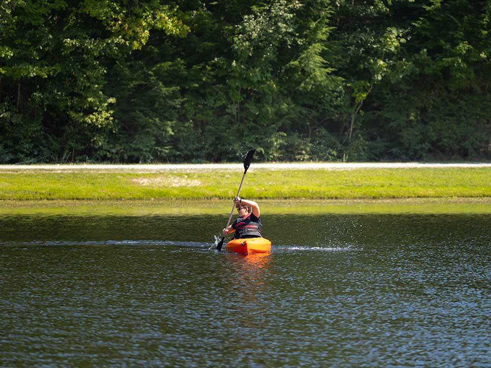 A young boy kayaking in the lake at JELLYSTONE PARK ™ AT BIRCHWOOD ACRES