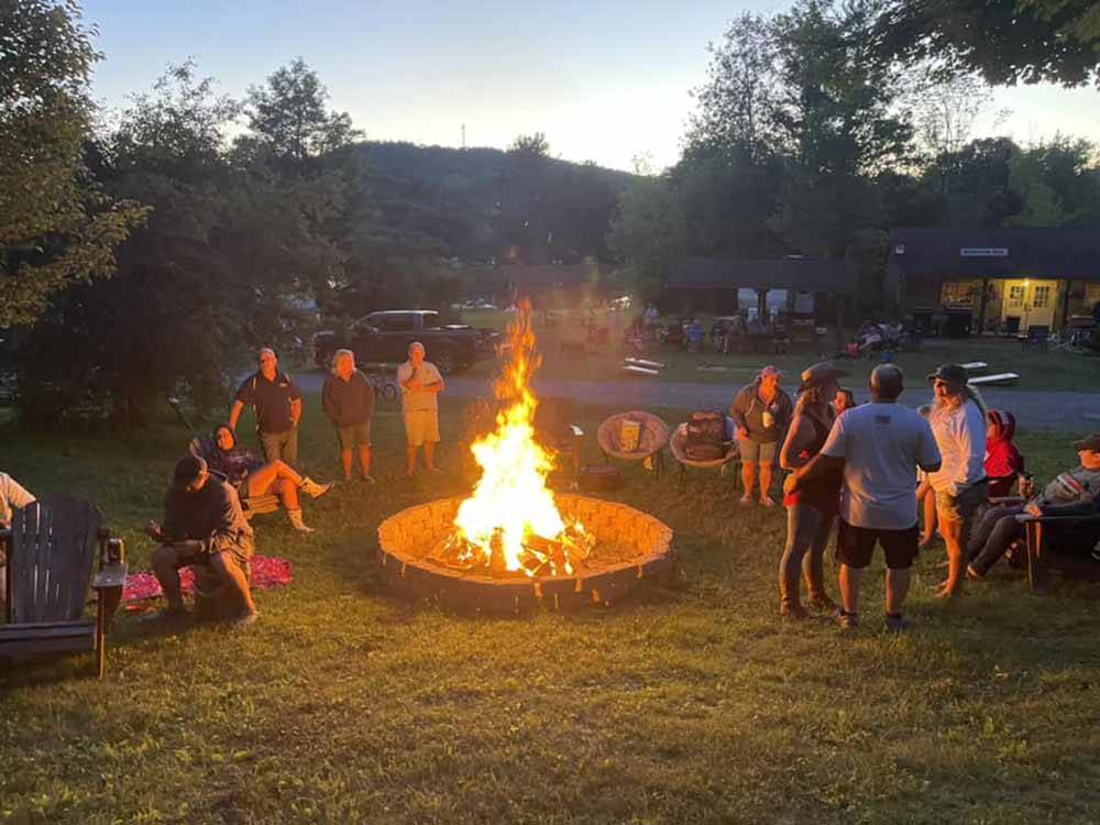 People standing around a bonfire at COOPERSTOWN SHADOW BROOK CAMPGROUND
