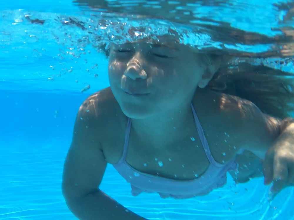 A girl swimming underwater in the pool at CROSSROADS TRAVEL PARK