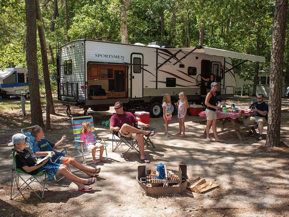Family gathered around travel trailer in campsite at OCEAN VIEW RESORT CAMPGROUND